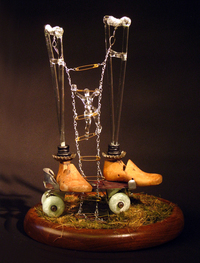 <div class='title'>Baby Steps</div><br>kiln-cast glass, flameworked glass, mirror, clock, artist-wrought chain, clock, grass, roller skate, safety pins, cobbler lasts, rubber grommets<br>19"h x 15"w x 11"d<br>SOLD