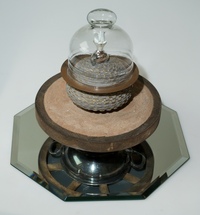 <div class='title'>Seed Safe</div><br>Flameworked points and vessel, vintage wagon wheel, silver server, mirror, fescue, sand, found glass dome, brass chain<br>11.5"h x 14"w x 14"d<br>